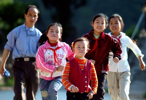 教师汪来九带着孩子们在室外跑步。